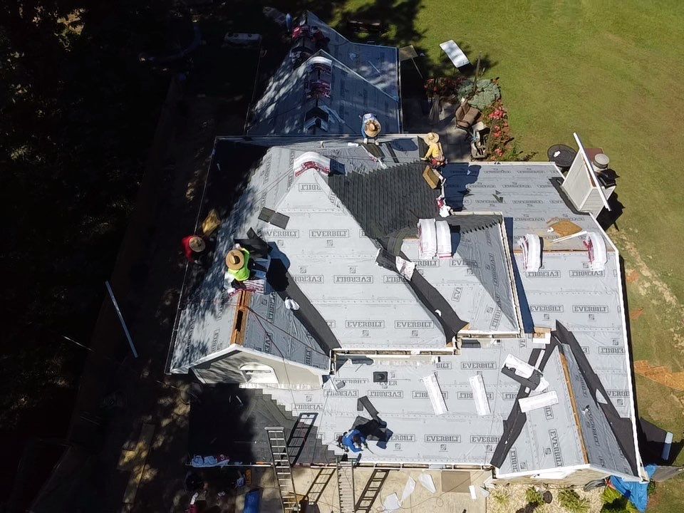 Aerial view — crew installing underlayment on residential roof